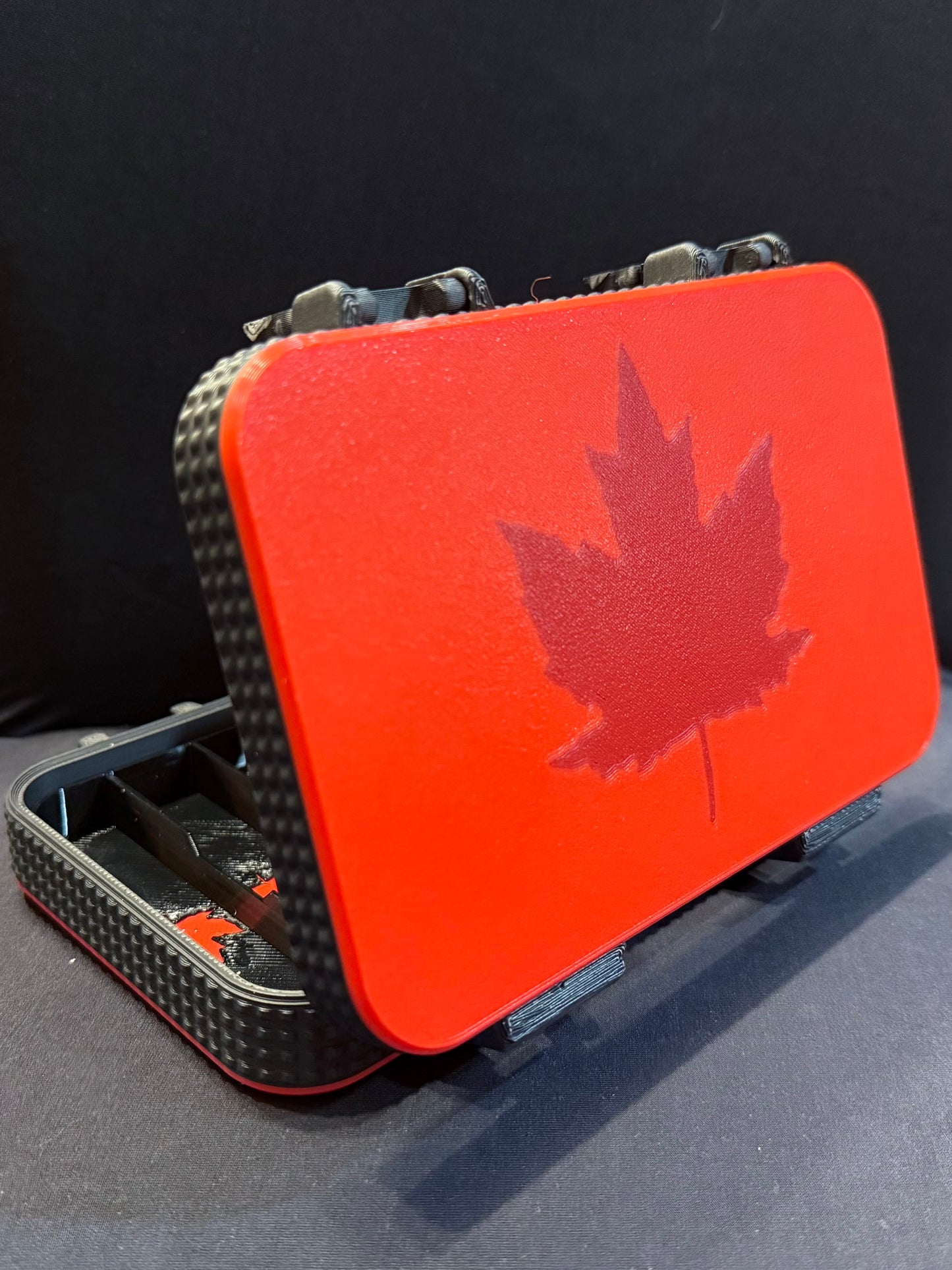 Rear angled vide of the open harmonica case in red and black with darker-red maple leaf details inside and out.