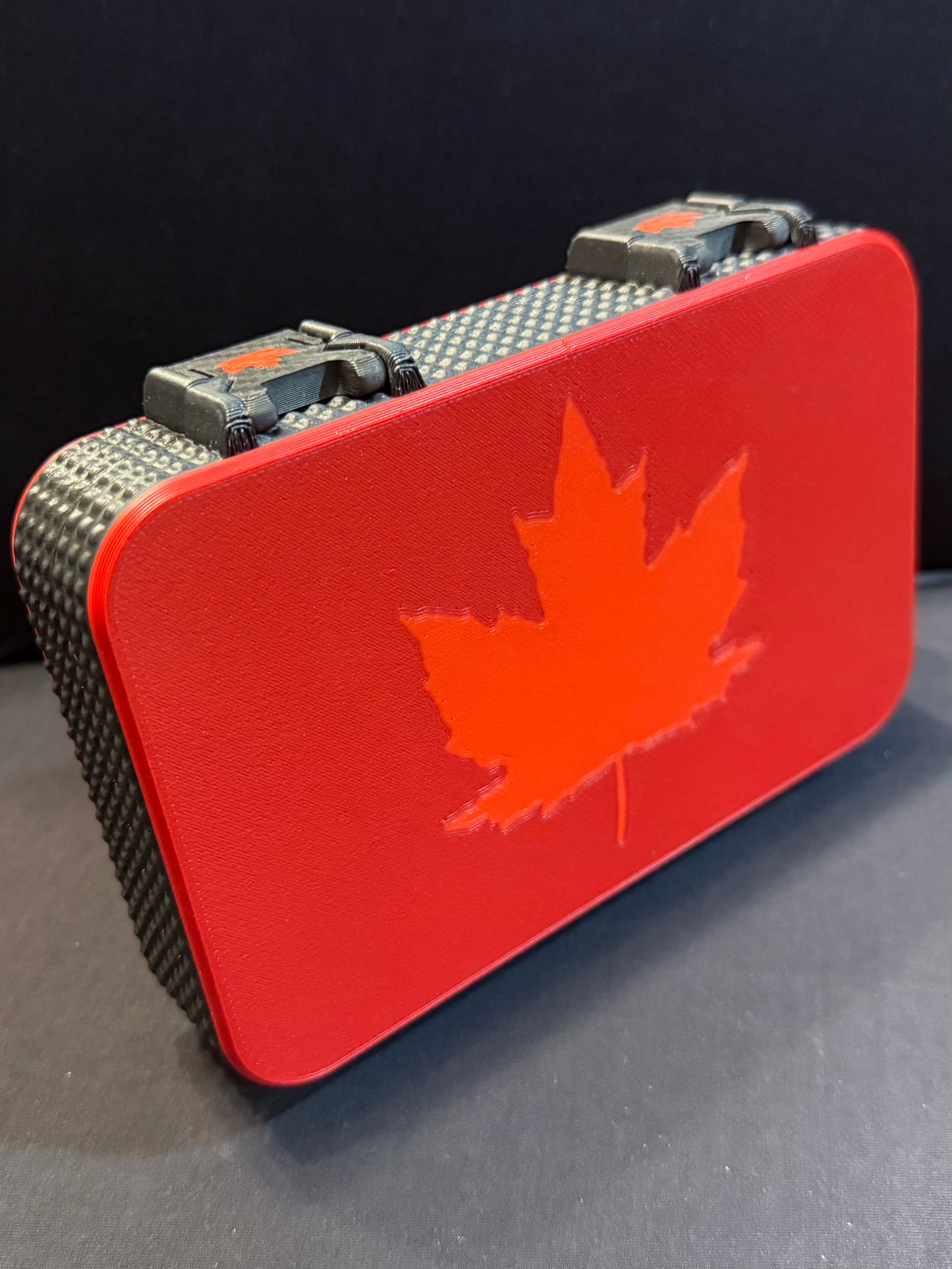 Front view of harmonica case with deep red shell and light red maple leaf design centered on the lid.
