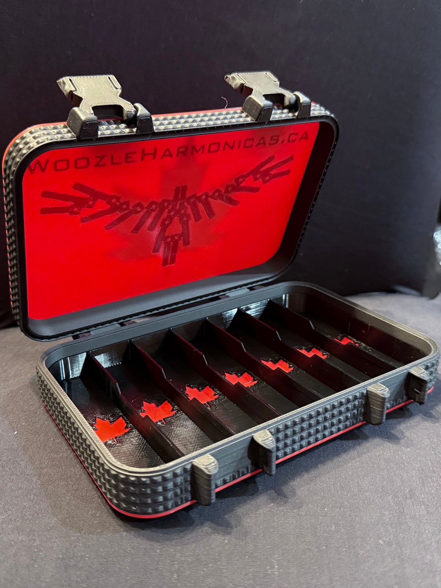 Open harmonica case in red and black with light red maple leaf details inside and the Woozle Harmonica logo on the underside of the lid.